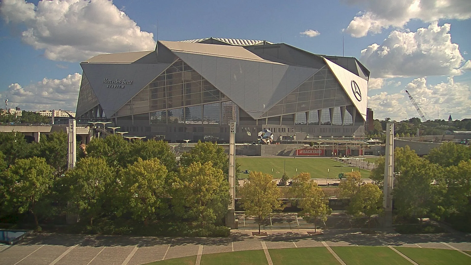 Mercedes-Benz Stadium in Atlanta, a striking grey stadium with angular architecture, surrounded by green space.
