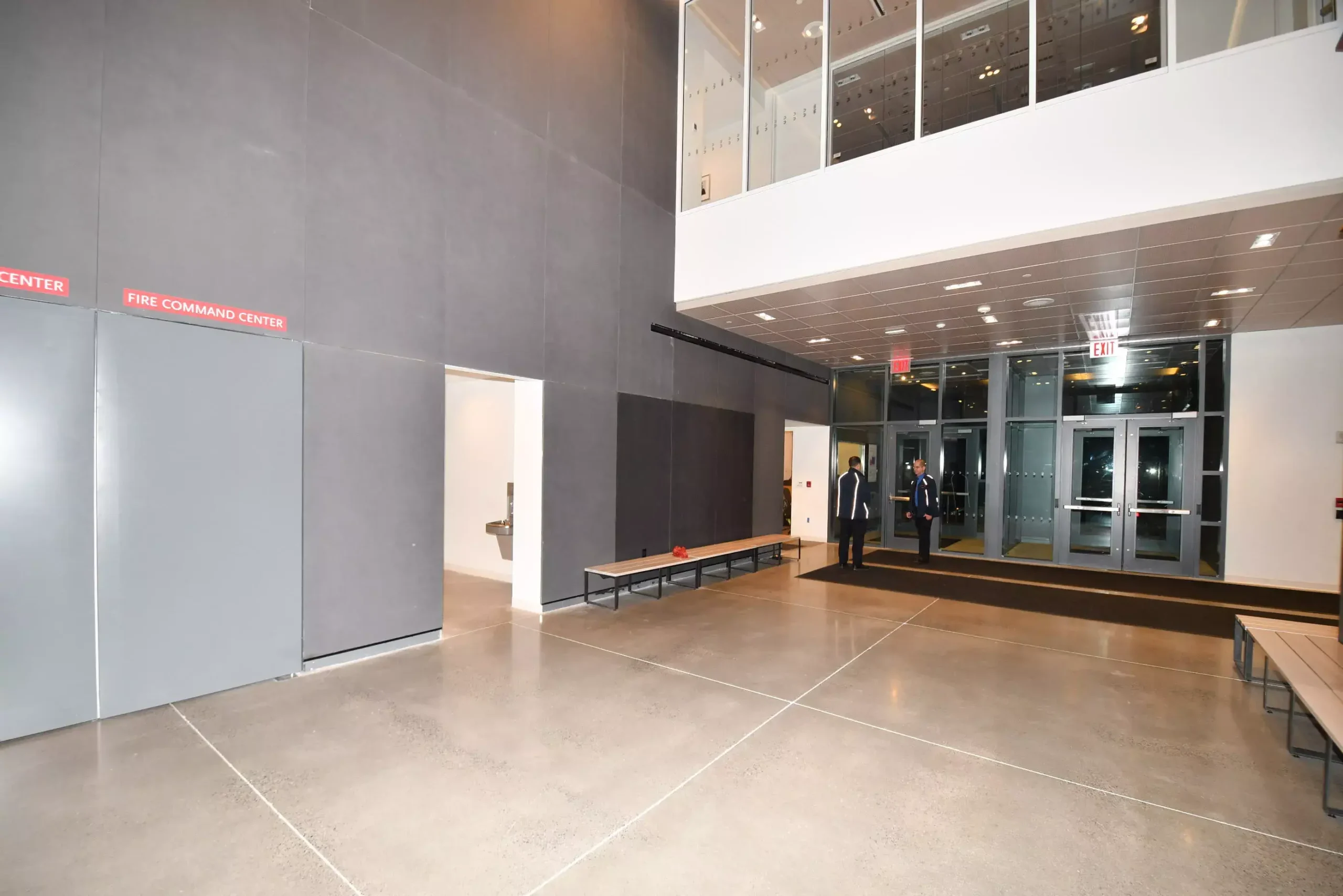 Spacious modern lobby with two security guards, Fire Command Center signs, and large exit doors.
