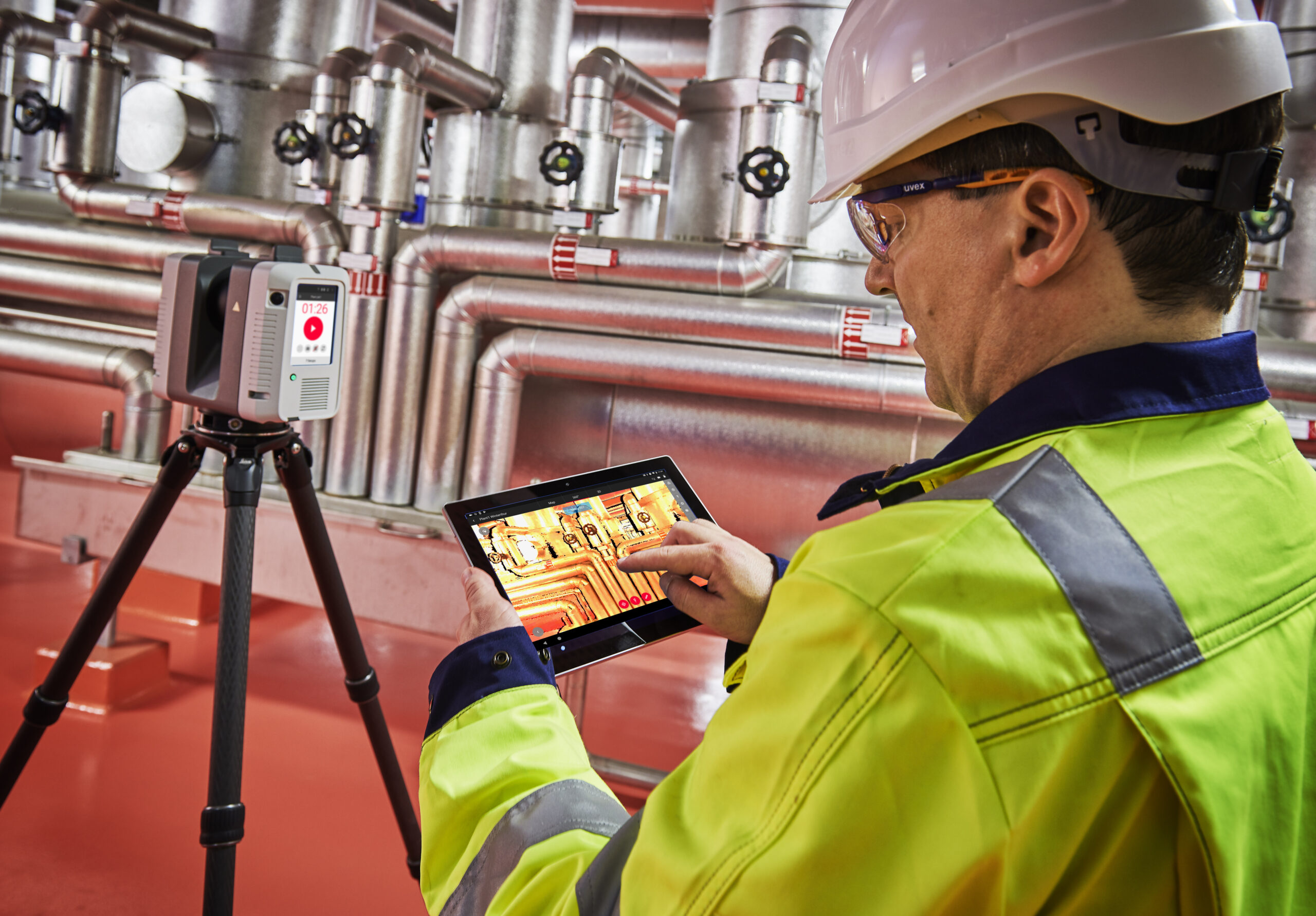 Engineer monitors industrial piping using a 3D laser scanner and reviews data on a tablet.