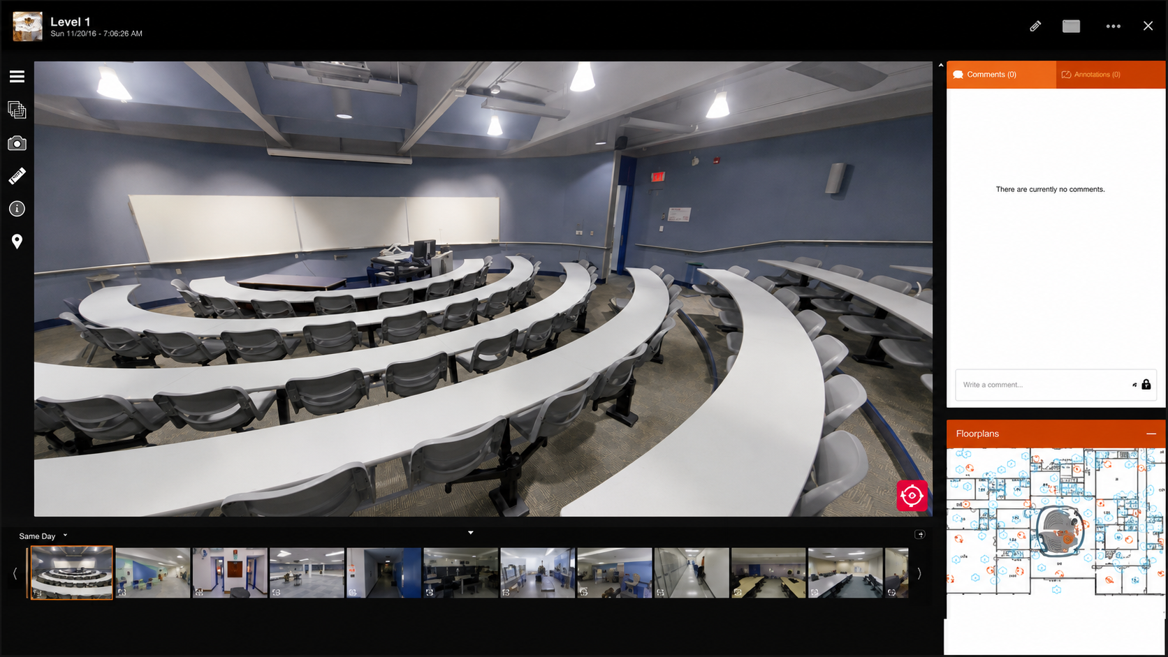Empty modern lecture hall with curved desks and grey chairs, whiteboards, and a teaching station.