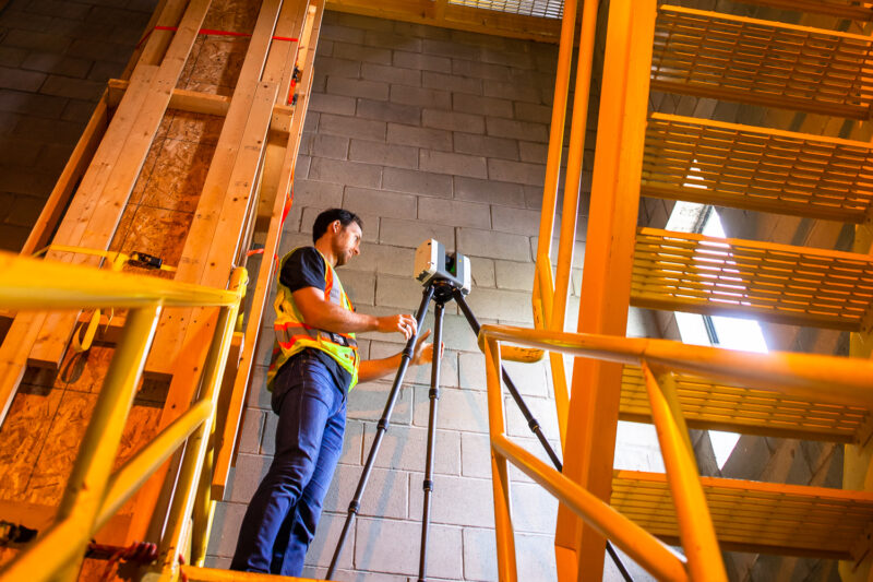 Construction documentation technician using a 3D Laser scanner to create scan to plan CAD files on a jobsite.