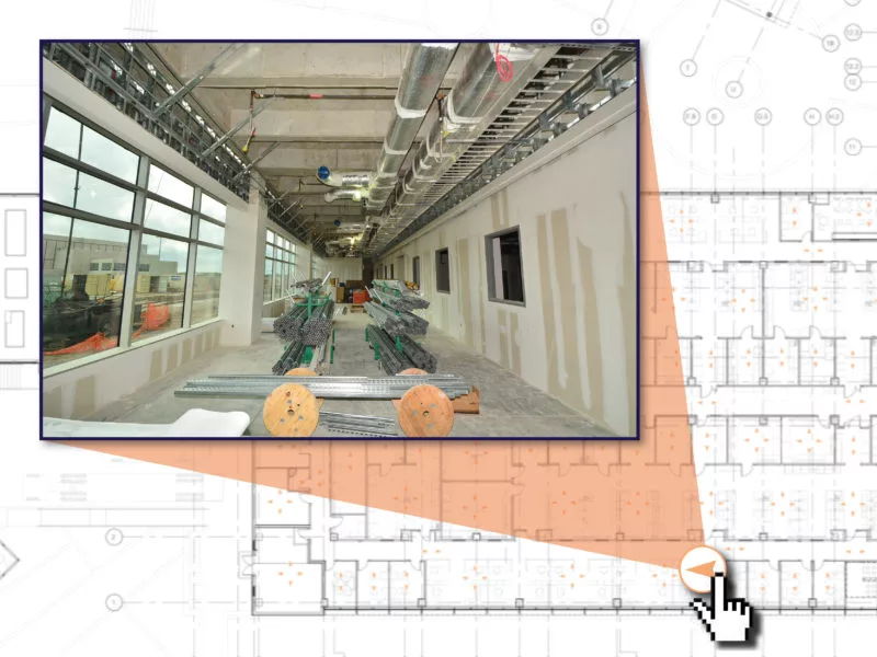 Under construction building interior with exposed utilities and materials, mapped onto a floor plan with a cursor.