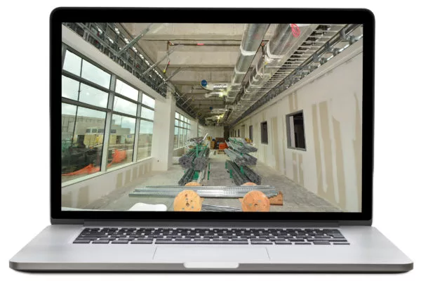 Laptop displaying an interior construction site with exposed ceilings, windows, and building materials.