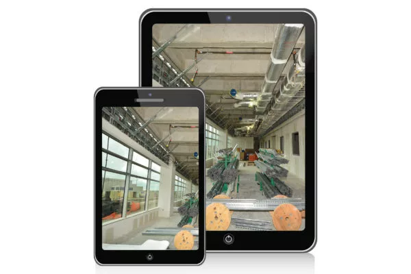 A smartphone and tablet display an industrial interior under construction with exposed ceiling ducts and materials.