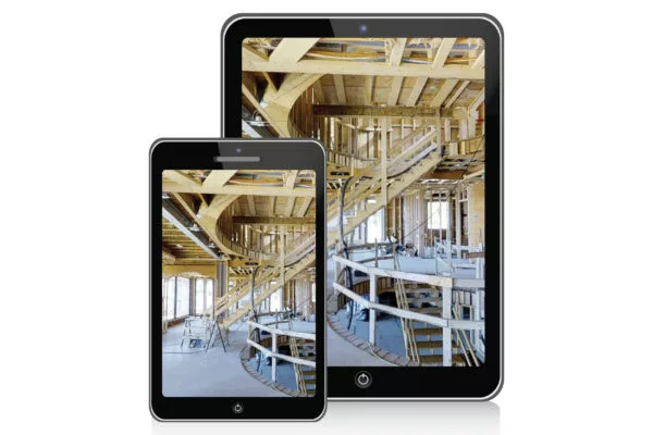 Smartphone and tablet displaying an unfinished building interior with exposed wooden framing and a spiral staircase.