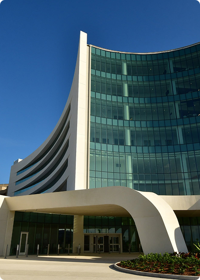 Modern curved building with glass facade and unique entrance under a blue sky.