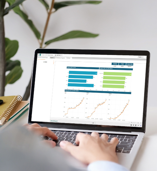 Hands typing on a laptop displaying a business analytics report with progress charts and graphs.