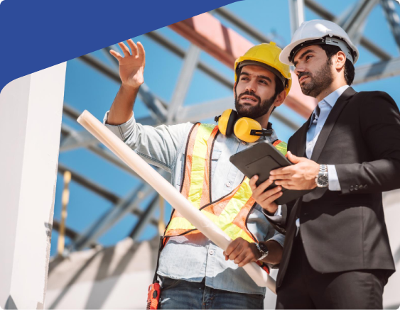 Construction worker and manager in hard hats discussing plans at a building site, with blueprints and tablet.