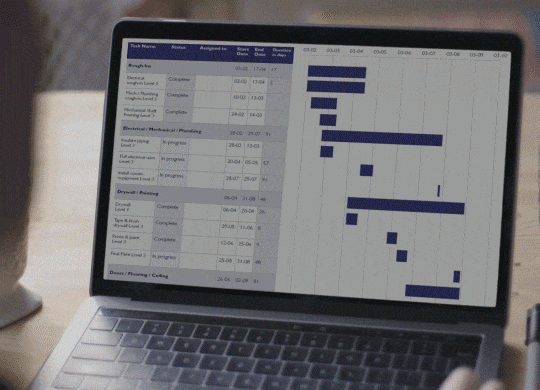 Laptop displaying a project management Gantt chart with tasks, statuses, dates, and progress bars for construction work.
