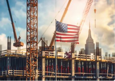 American flag waving over a city construction site with cranes and a growing skyline.