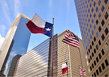 Texas and USA flags fly high among modern city skyscrapers.