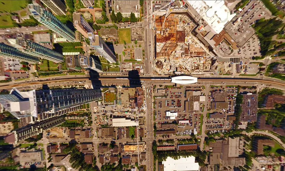Aerial view of a bustling urban landscape with skyscrapers, a train station, commercial buildings, and a large construction site.