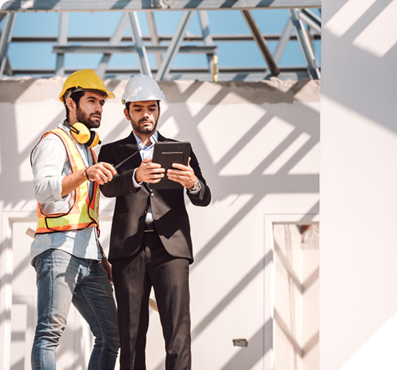 Construction worker and architect reviewing plans on a tablet at a building site.