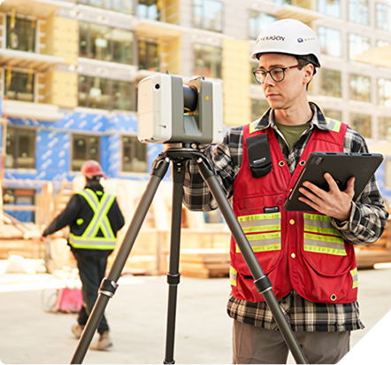 Surveyor scanning a construction site with a 3D laser scanner and tablet.