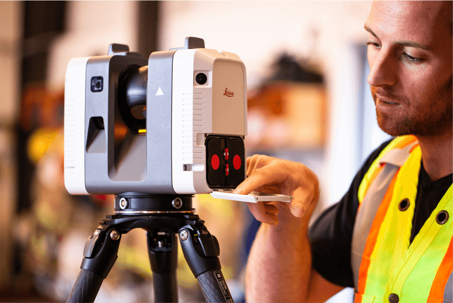 Man in safety vest adjusting a Leica laser scanner on a tripod.