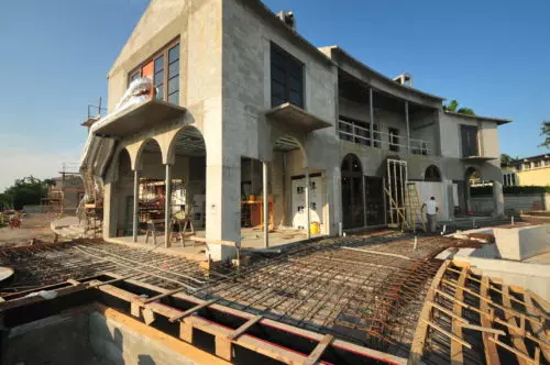 Multi-story concrete house under construction with arches and rebar for a new foundation or patio.