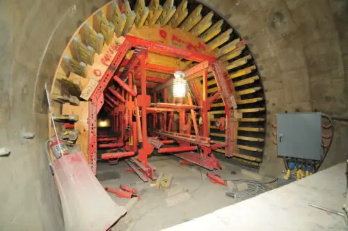 Inside a concrete tunnel under construction with a large red formwork machine.