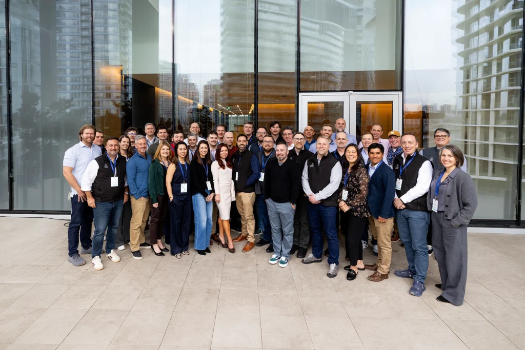 Large group of diverse business professionals posing outside a modern glass building.