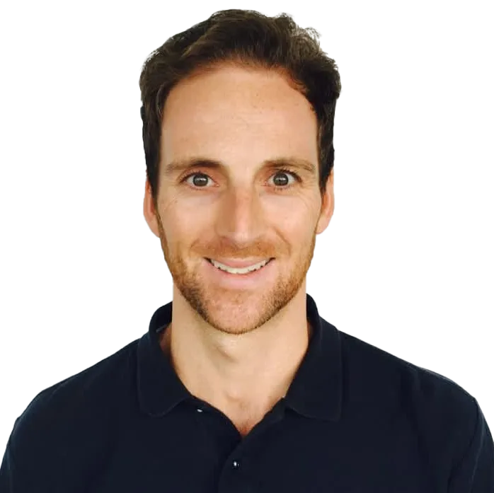 Smiling man with brown hair and light stubble wearing a dark polo shirt.