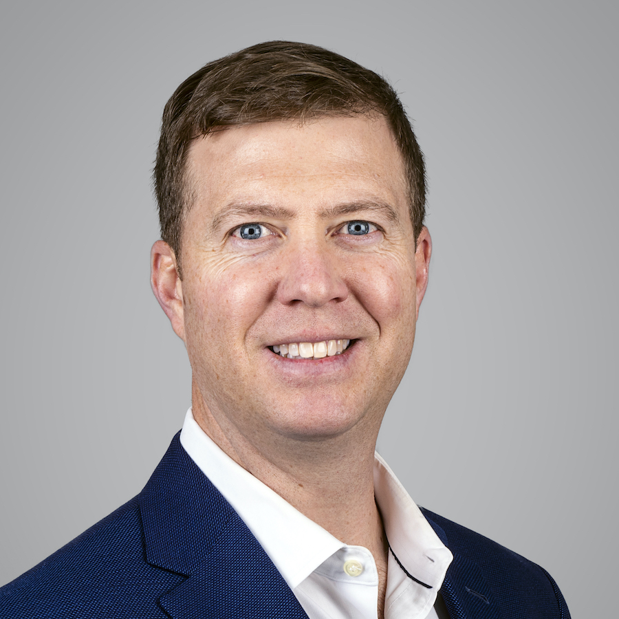 Smiling man with brown hair and blue eyes in a blue suit.