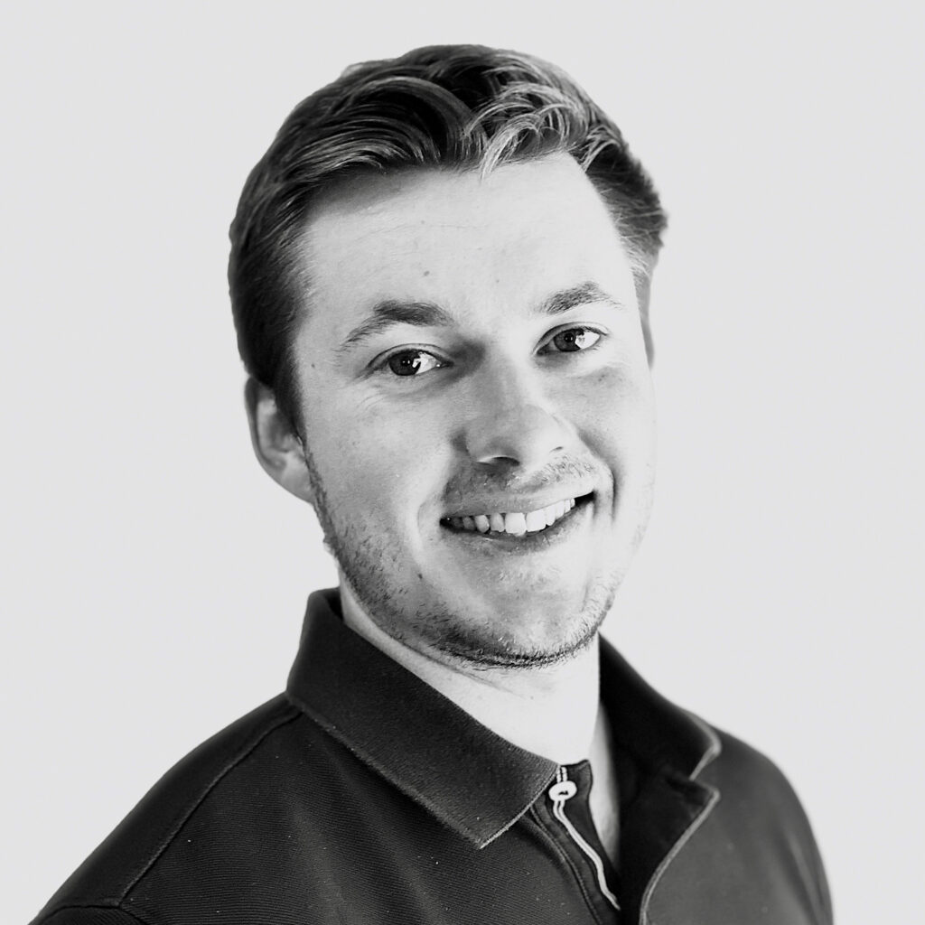Black and white portrait of a smiling young man in a polo shirt.