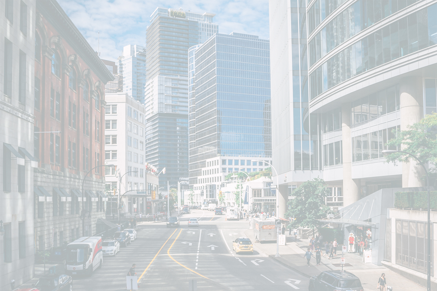 Bustling city street with a mix of historic brick buildings and modern glass skyscrapers, cars, and pedestrians.
