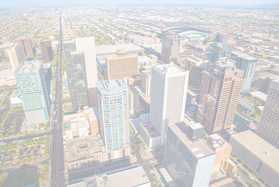 Aerial view of downtown Phoenix cityscape with modern high-rise buildings, busy streets, and a stadium.