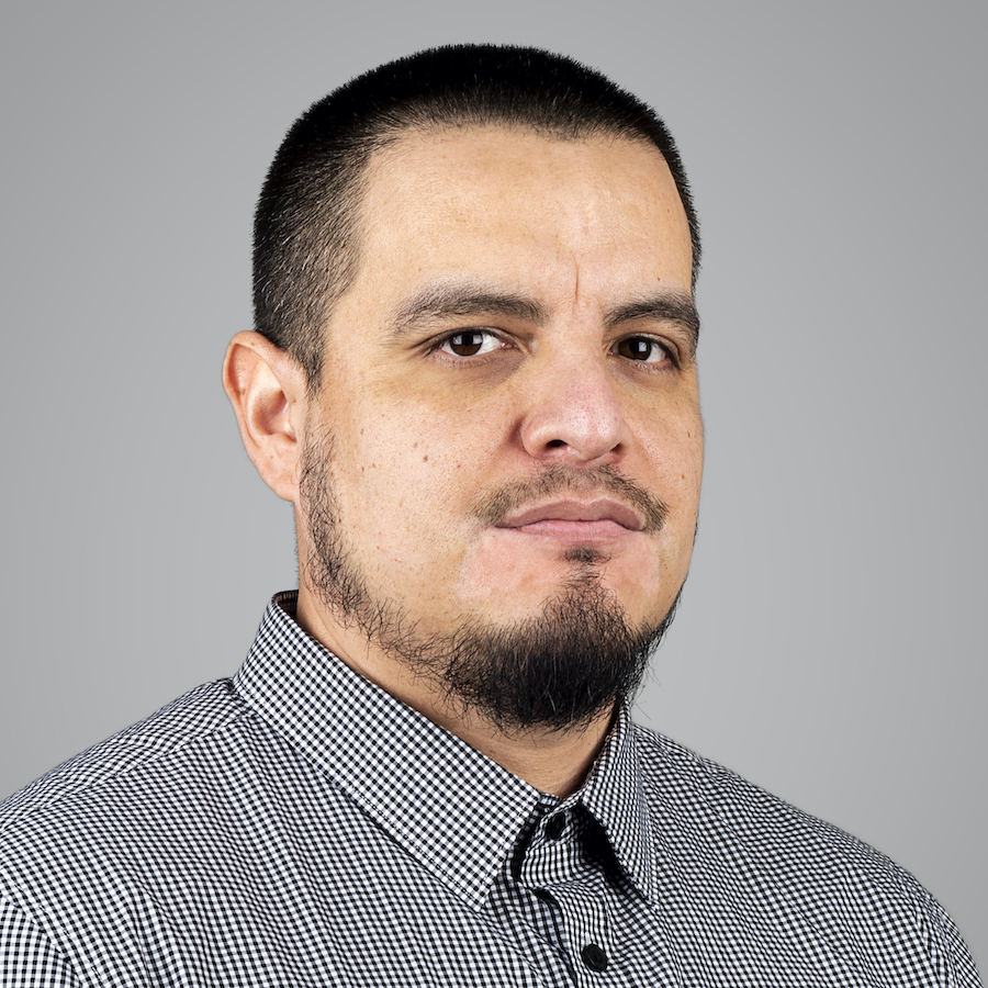 Man with a beard, short hair, and vitiligo on his face, wearing a black and white checkered shirt.