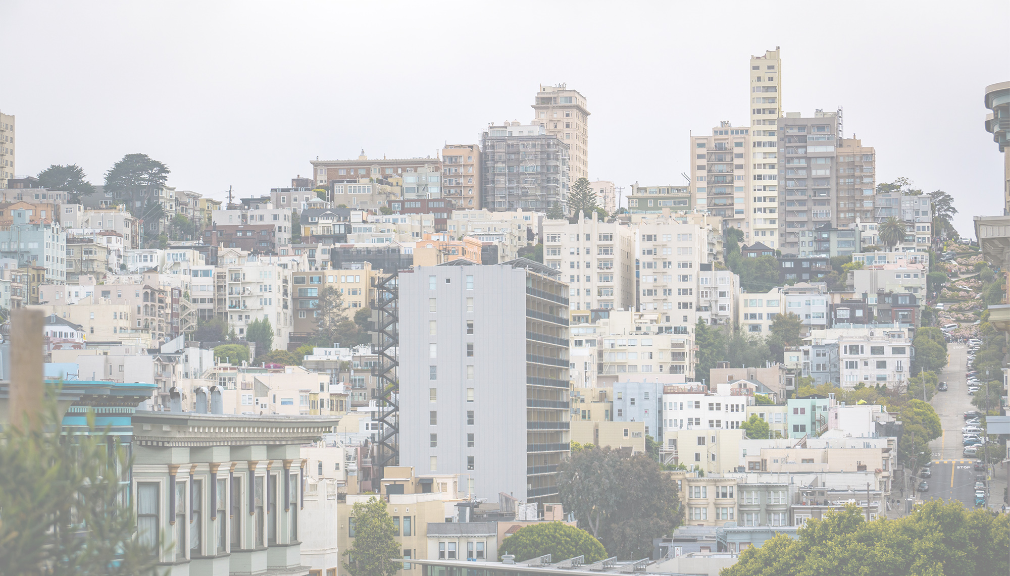 Hilly San Francisco cityscape showing a mix of historic and modern buildings and a winding street.