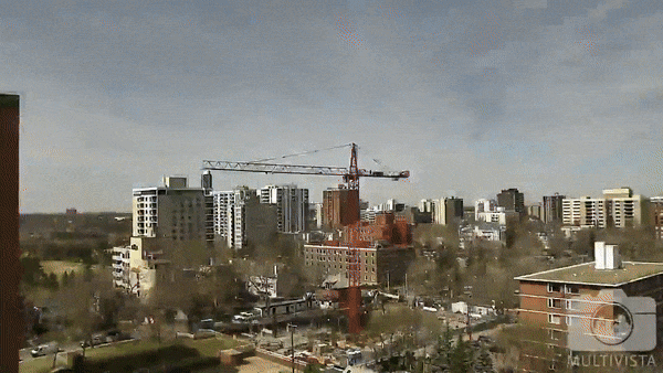 Urban cityscape with a large red construction crane towering over buildings and ongoing development.