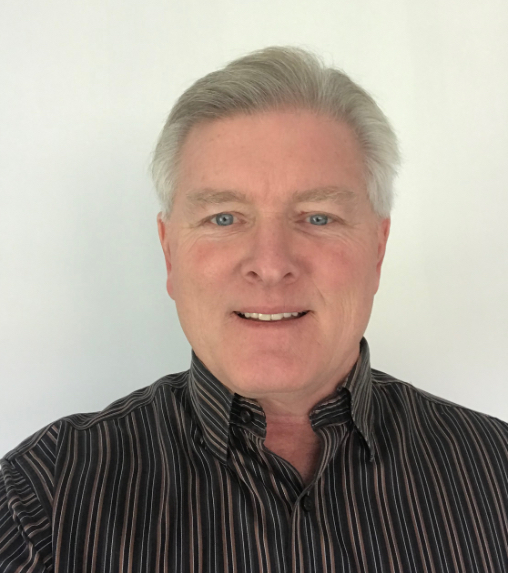 Professional headshot of a smiling man with grey hair and blue eyes in a striped shirt.