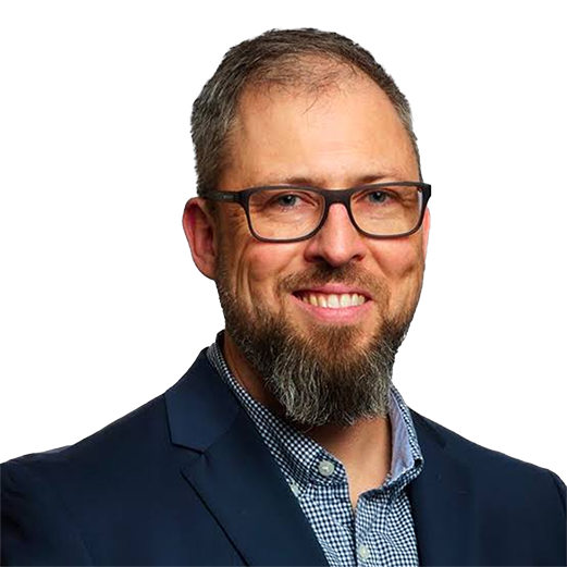 Headshot of a smiling man with a beard, glasses, and blue blazer.