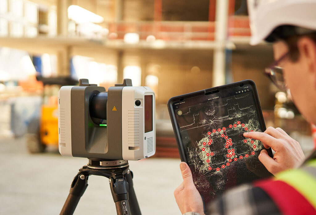 Worker uses a 3D laser scanner to survey a construction site, viewing the digital map on a tablet.